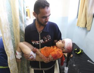 Man carries injured Palestinian girl after airstrike in Gaza