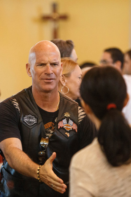 Congregants exchange the sign of peace at a Mass in February before a charity motorcycle ride led by Miami Archbishop Thomas G. Wenski to benefit a Catholic Charities' center for alcohol and drug rehabilitation. (CNS/Tom Tracy)