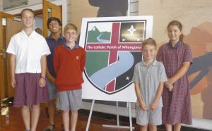 A logo competition was held to refl ect the new parish. The winning entry was publicly displayed at the reunifi cation Mass, with the winner asking to remain anonymous. The logo depicts the river fl owing from the mountain and the waters moving past special places along its way to the ocean. Stars of the Southern Cross also feature. Standing next to the logo are St Anne’s School students, from left: Emma Forlong, Tamasi Connor, Sebastion and Romeo Newton and Zoe Forlong.