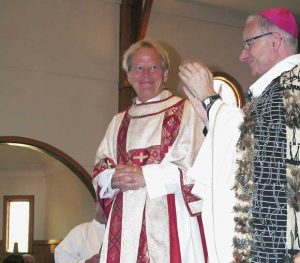 Bishop Charles Drennan, right, congratulates new transitional deacon Bryan Buenger.