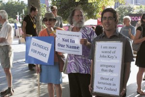 Robyn Lang, left, holds a Catholics for Peace sign during the vigil next to Aotea Square.