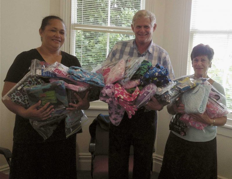 From left, Lesina Vete from Sacred Heart parish and, from  Catholic Social Services, director John Metherell and
receptionist Judy Olsen, with an armload of donated pyjamas.