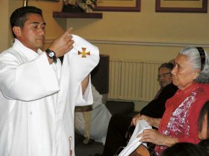 Deacon Lam gets family help to dress in his clerical vestments.
