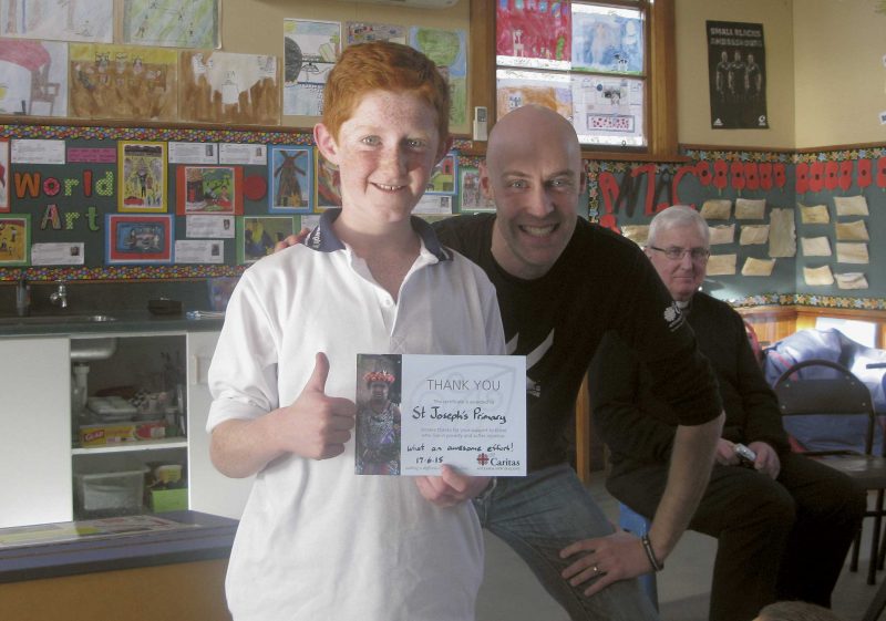 Michael Stewart, Caritas’s Social Justice Education Coordinator, gives a thank you card to a young representative of the school’s pupils. Mackenzie parish priest Fr John Morrison is in the background.