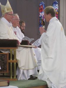 Bryan Buenger kneels before Bishop Charles Drennan and Emeritus Bishop Owen Dolan during the ordination ceremony. Photo by Sue Seconi