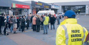 Pacific wardens keep an eye on what is happening at a protest in Glen Eden over the impending closure of the township’s Postshop. Note the two wardens in the distance.