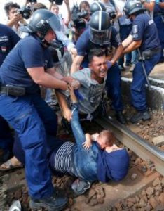 Hungarian policemen detain migrants on the tracks at a railway station in the town of Bicske, Hungary, Sept. 3. (CNS photo/Laszlo Balogh, Reuters) See MIGRANTS-EUROPE-NICHOLS Sept. 3, 2015.