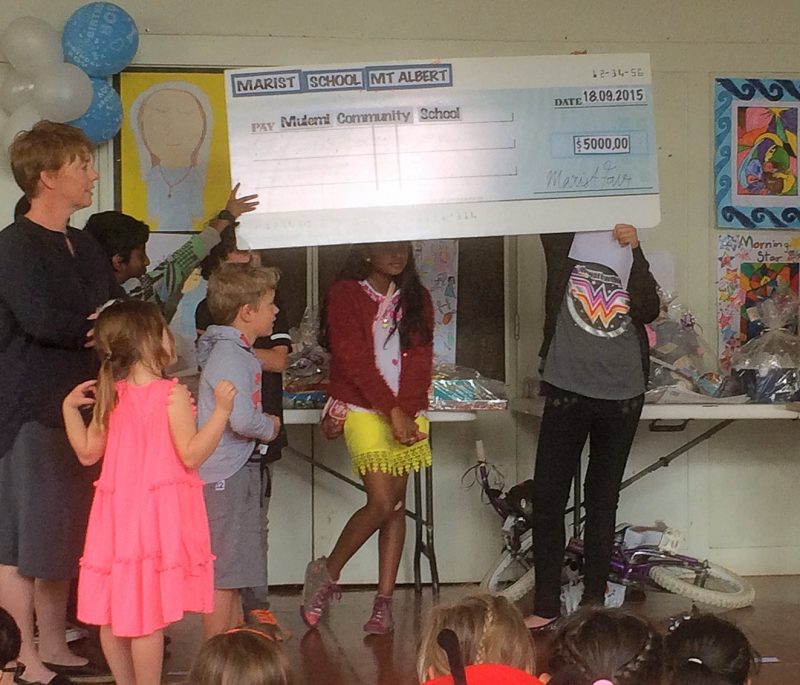 The $5000 cheque for the Mulemi Community School. At left are Leanne Cameron and two of her children, Louis and Fenn.