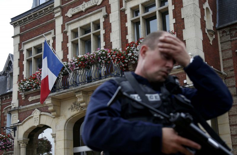 A policeman reacts as he secures a position in front of city hall after two assailants killed 84-year-old Father Jacques Hamel and took five people hostage during a weekday morning Mass  at the church in Saint-Etienne-du-Rouvray, France, near Rouen July 26. (CNS photo/Pascal Rossignol/Reuters) See POPE-FRENCH-HOSTAGE July 26, 2016.