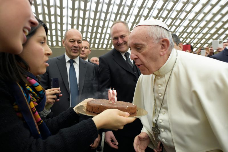 Pope Francis blows out candles on a birthday cake presented by a woman during his general audience in Paul VI hall at the Vatican Dec. 14. The pope will turn 80 Dec. 17. (CNS photo/L'Osservatore Romano, handout) See POPE-AUDIENCE-NEW-HOPE Dec. 14, 2016.