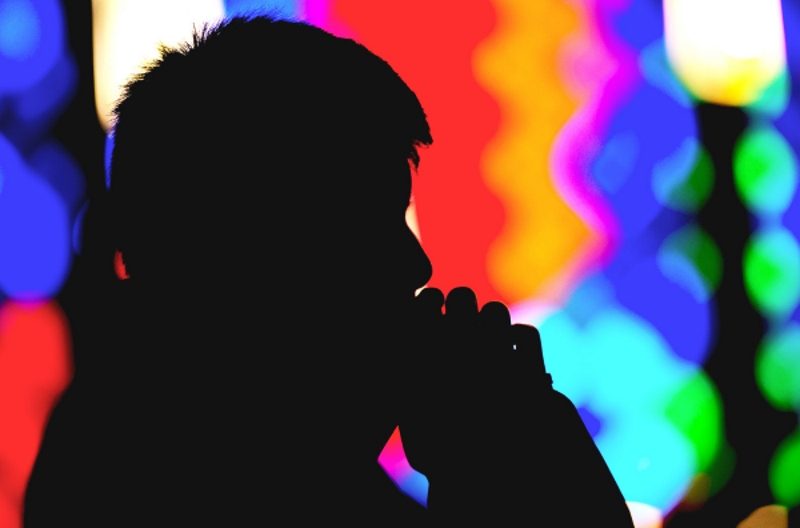 Fourteen-year-old Oscar Kha is silhouetted as he prays during a Nov. 23 Mass at St. John the Evangelist Church in Greece, N.Y. (CNS photo/Mike Crupi, Catholic Courier)