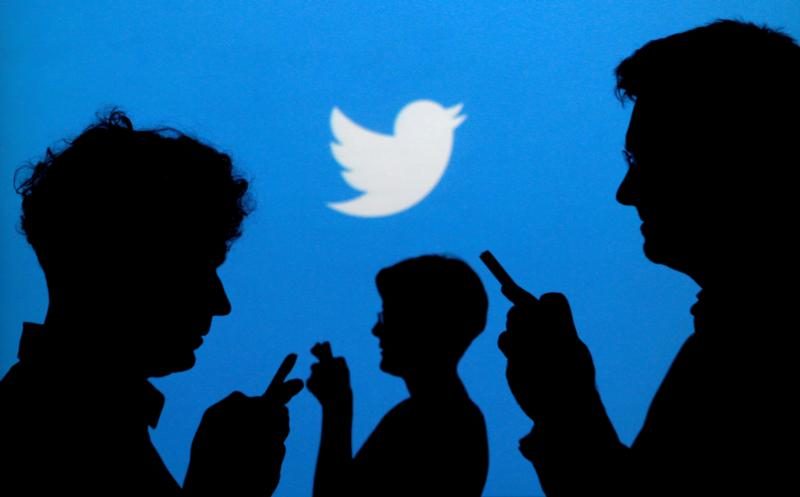 People use mobile phones in front of the Twitter logo in this 2013 illustration photo. Pope Francis' @Pontifex Twitter accounts reached more than 40 million followers just a few months before the fifth anniversary of when Pope Benedict XVI launched the initiative. (CNS photo/Kacper Pempel, Reuters) See POPE-TWITTER-INSTAGRAM Oct. 11, 2017.