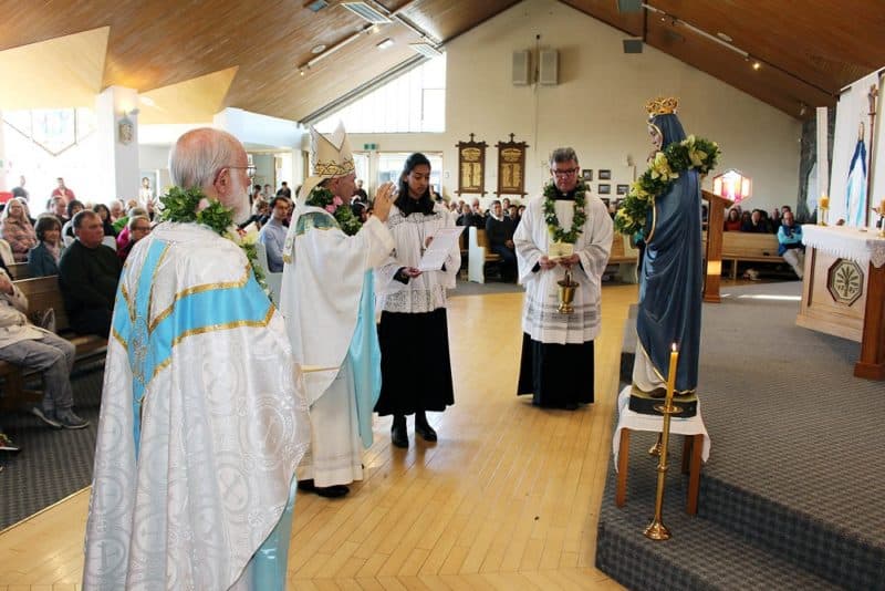 Bishop Michael Gielen prays before the statue, watched by Fathers Terry Montgomery (left) and John Fitzmaurice.
