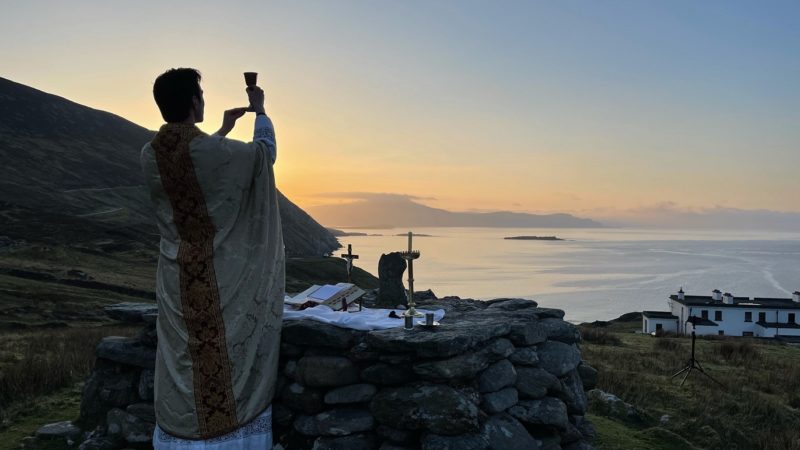 Father Gerard Quirke raises the chalice at Mass Rock overlooking Keem Bay on Ireland's Achill Island April 4, 2021. Father Quirke, a priest of the Archdiocese of Tuam, said celebrating Easter Mass there had a "particular resonance" given the current legal ban on Masses in Ireland. (CNS photo/Seán Molloy, courtesy Irish Catholic)