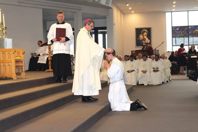 Bishop Stephen Lowe lays hands on Fr Fransen during the ordination.