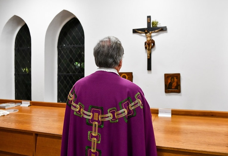 A priest prays in front of the crucifix in the sacristy before Mass in Bonn, Germany, Jan. 24, 2018. Bishop Felix Genn of Münster, Germany, who co-chairs the Synodal Path's forum on priests, said he is skeptical about exempting Catholic priests from celibacy. (CNS photo/Harald Oppitz, KNA)