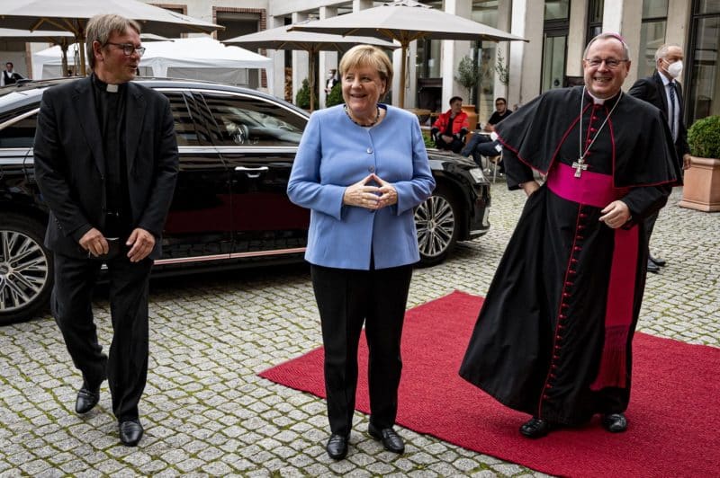Bishop Georg Bätzing, right, president of the German bishops' conference, is pictured with German Chancellor Angela Merkel at the annual St. Michael's reception in Berlin Sept. 27, 2021. Also pictured is Father Karl Jüsten, an official of the German bishops' Conference. In an address at the conference, Bishop Bätzing criticized the Vatican's stance of refusing blessings for same-sex couples and the way it has dealt with German bishops embroiled in covering up sexual abuse in their dioceses. His speech was delivered in the presence of some 200 faith representatives and politicians. (CNS photo/Fabian Sommer, KNA pool)