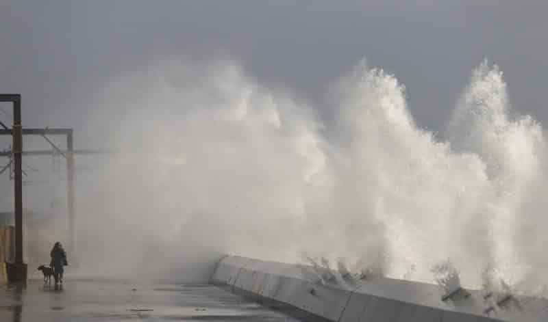 A man walks his dog as waves crash against a seawall in Saltcoats, Scotland,  Feb. 9, 2020. In a letter to Catholics in Scotland published Nov. 11, 2021, Pope Francis warned that time is running out in preventing climate change and that failing to protect the environment could incur "God's judgment." (CNS photo/Eddie Keogh, Reuters)