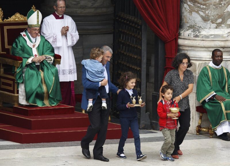Pope Francis watches as a family carries offertory gifts to the altar during a Mass for catechists in St. Peter's Square at the Vatican in this Sept. 29, 2013, file photo. In a document released May 11, 2021, Pope Francis  instituted the "ministry of catechist." (CNS photo/Paul Haring)