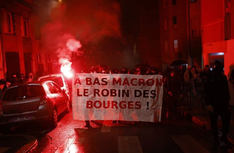 People attend a demonstration after the announcement of results of the 2022 French presidential election in Lyon, France, April 24, 2022. The banner reads: "Down with Macron, Robin (Hood) of the bourgeoisie." (CNS photo/Stephane Mahe, Reuters)