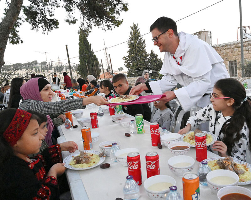 French Dominican Father Oliver Catel serves Muslims during an iftar at Abraham's House on the Mount of Olives in East Jerusalem April 9, 2022. The meal offered by Christian volunteers to Muslim neighbors on the eve of Palm Sunday served as testimony to the principles of peace and fraternity, said the event's organizers. (CNS photo/Debbie Hill)