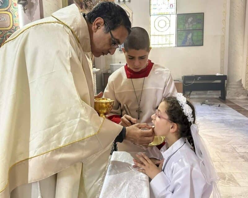 On Jan. 7, 2024, the feast of Epiphany, Father Youssef Asaad, an assistant priest at the Holy Family Parish in Gaza City, administers the sacrament of first Communion to one of eight children of the parish after they completed their preparation program and education, despite the ongoing Israel-Hamas war. (OSV News photo/courtesy Latin Patriarchate of Jerusalem)