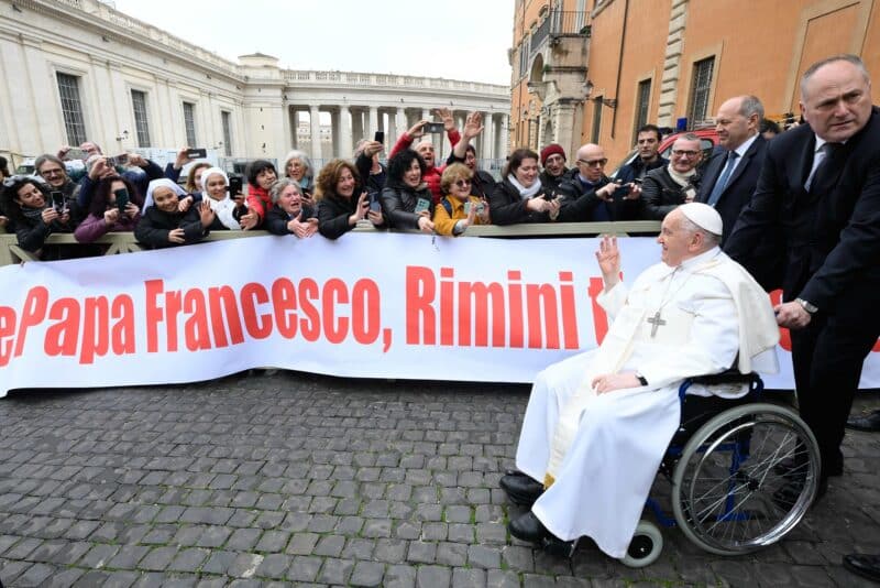 As Pope Francis exits the Paul VI Audience Hall after his weekly general audience at the Vatican on Feb. 28, 2024, a group of people extends their greetings to him. (CNS photo/Vatican Media)
